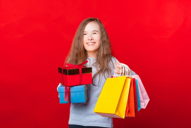 두 개의 선물 상자와 많은 다채로운 쇼핑 가방을 들고 멀리보고 행복 한 아이
