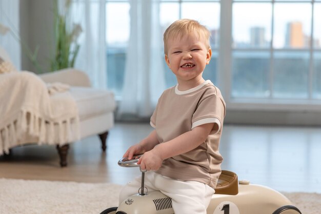Счастливый ребенок дома маленький мальчик за рулем большой винтажной игрушечной машины и весело улыбающийся ребенок играет