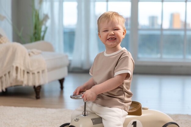 Happy child at home little toddler boy driving big vintage toy car and having fun smiling kid playin