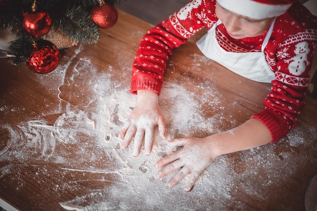 幸せな子供はクリスマスイブ メリー クリスマスとメリー正月の家族の休日に家の台所でお祝いのクリスマス クッキーを準備しています。