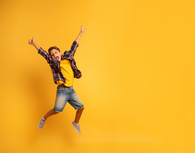 Happy child jumping over a yellow background