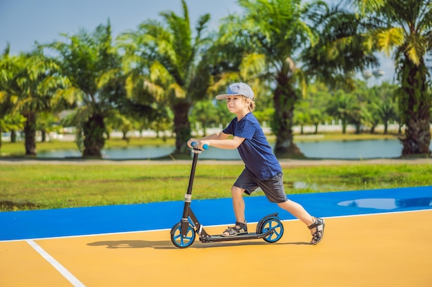 Happy child on kick scooter in on the basketball court kids learn to skate roller board little boy