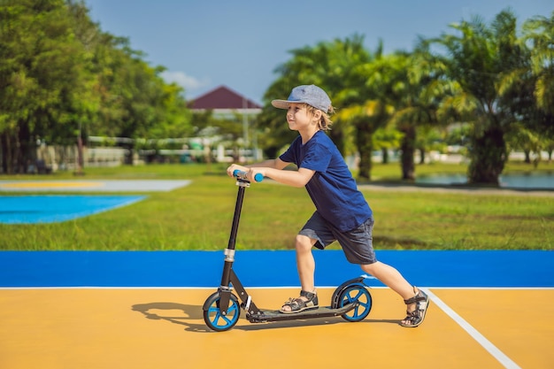 Happy child on kick scooter in on the basketball court kids learn to skate roller board little boy