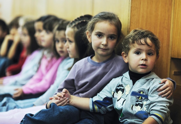 幸せな子供の子供たちのグループは、先生と一緒に幼稚園の屋内就学前教育のコンセプトで楽しく遊びます