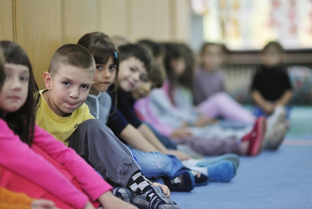 幸せな子供の子供たちのグループは、先生と一緒に幼稚園の屋内就学前教育のコンセプトで楽しく遊びます