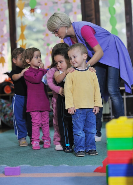 группа счастливых детей развлекается и играет в детском саду в помещении концепции дошкольного образования с учителем