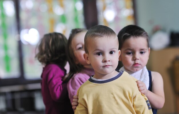 幸せな子供の子供たちのグループは、先生と一緒に幼稚園の屋内就学前教育のコンセプトで楽しく遊びます