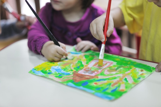 幸せな子供の子供たちのグループは、先生と一緒に幼稚園の屋内就学前教育のコンセプトで楽しく遊びます