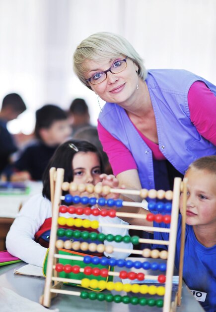 Foto il gruppo di bambini felici si diverte e gioca al concetto di educazione prescolare al coperto dell'asilo con l'insegnante