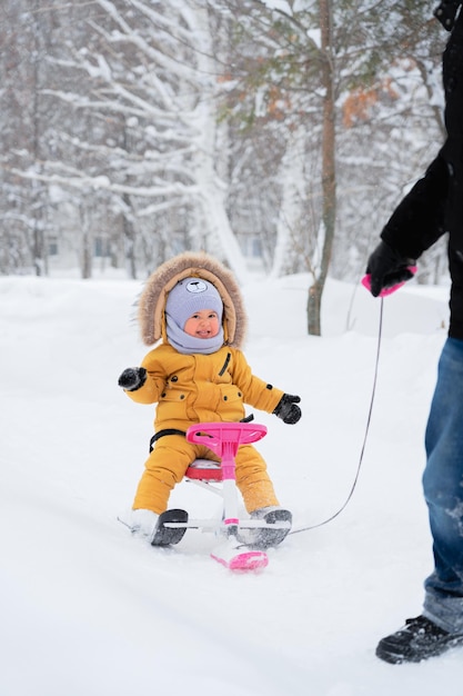 행복한 아이가 겨울 공원에서 어린이 스노우캣을 타고 웃는다