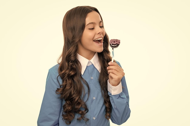 Happy child long curly hair eat chocolate candy on stick\
isolated on white yummy