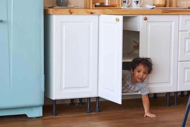 A happy child looks out of the closet in the kitchen