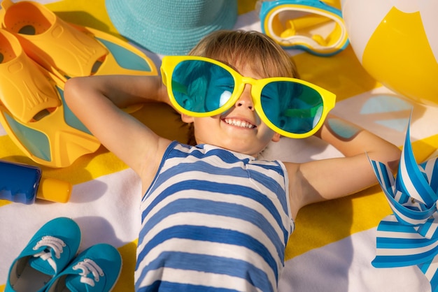 Счастливый ребенок лежит на пляжном полотенце Забавный ребенок на открытом воздухе на летних каникулах