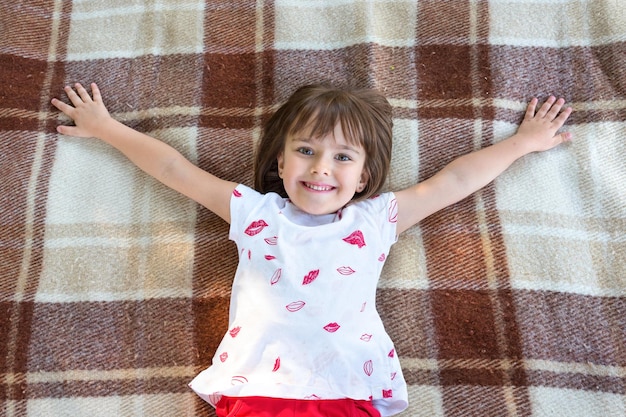 The happy child lying on a plaids in the park and Top view