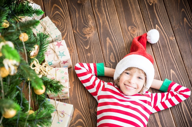 Happy child lying on wooden floor. Funny kid on Christmas eve. Xmas holiday concept