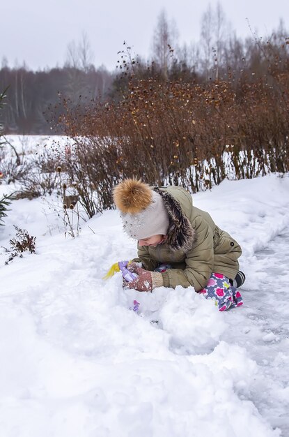 Happy child make a snowman in a snow-covered field in the countryside.