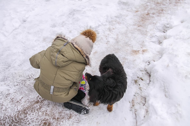 幸せな子供は田舎の雪に覆われたフィールドで雪だるまを作ります。