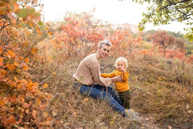 Happy child and mother with golden and red trees