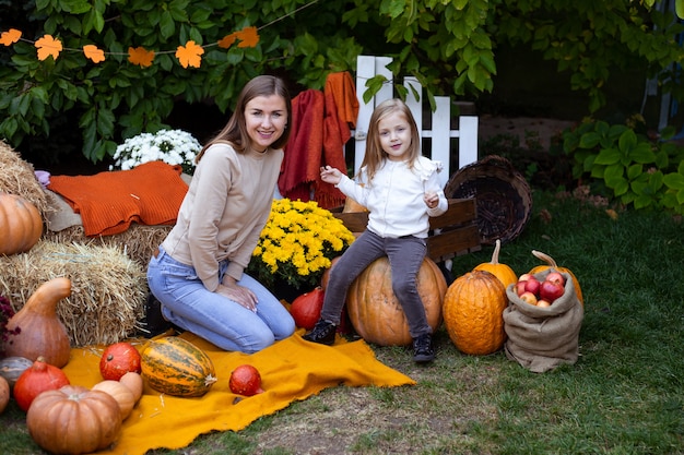 幸せな子供とハロウィーンの屋外でカボチャを持つ母