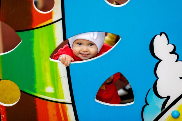 Happy child on Playground. Baby hides behind shield and looks out through hole