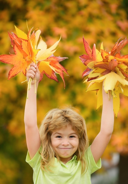 Happy child playing in the autumn park on the nature walk outdoors