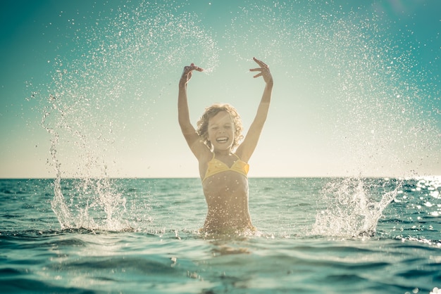 Happy child playing in the sea. Kid having fun on summer vacation. Healthy active lifestyle concept