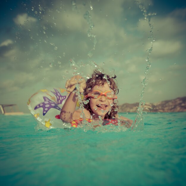 Foto bambino felice che gioca in piscina focus su splash