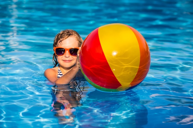 Счастливый ребенок, играющий в бассейне