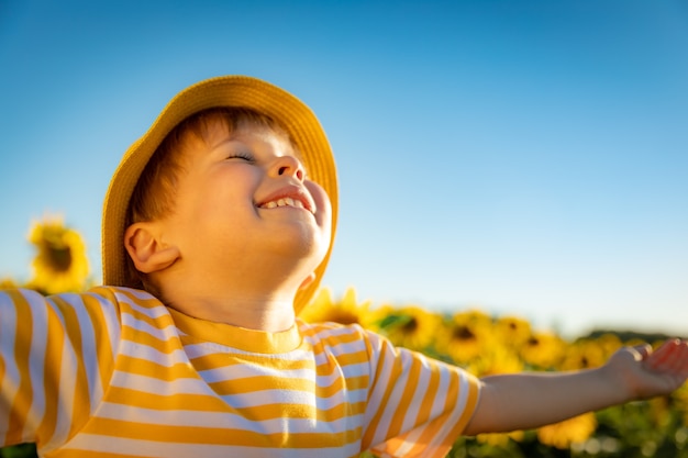 Happy child playing with sunflower outdoor