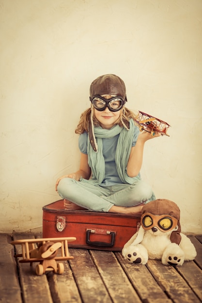 Happy child playing with toy airplane at home. Retro toned