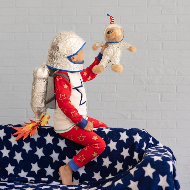 Happy child playing with toy rocket against brick wall background