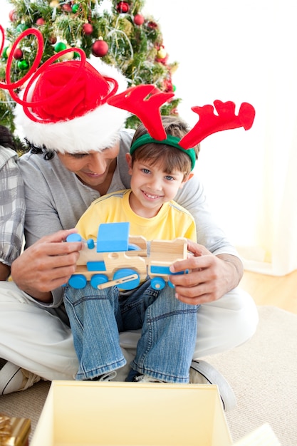 Happy child playing with a train with his father