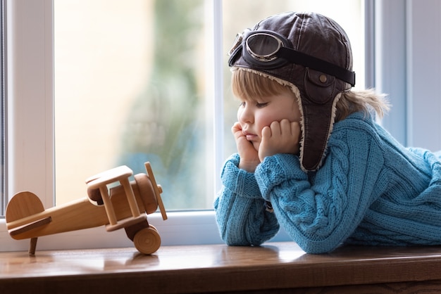 Happy child playing with vintage wooden airplane indoor.