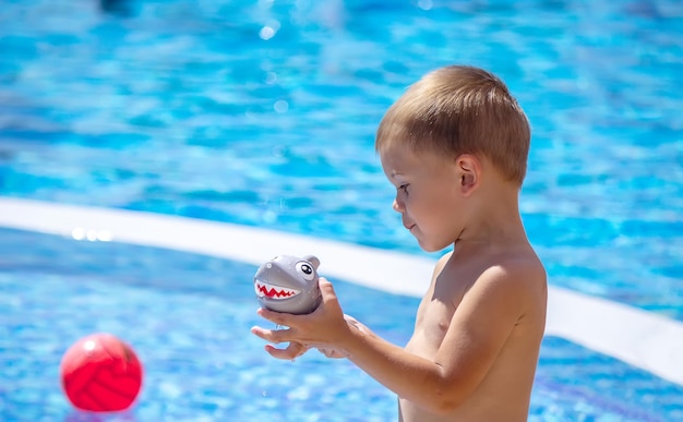 Happy child in the pool playing with a water gun.