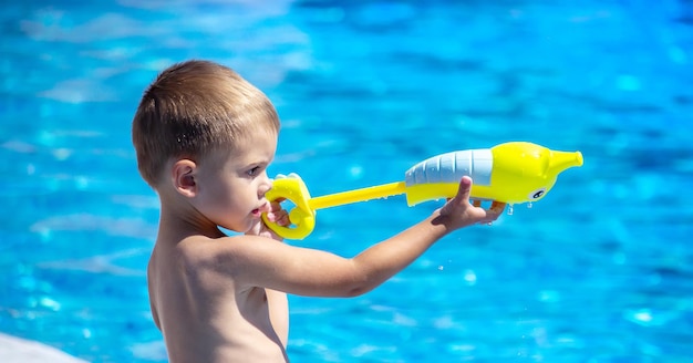 Happy child in the pool playing with a water gun.