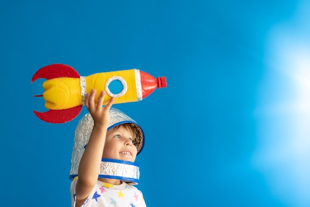 写真 幸せな子供は青い背景に対して宇宙飛行士の子供の肖像画のふりをします