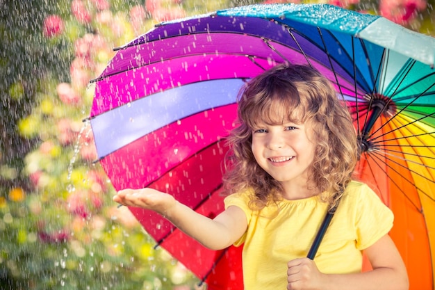 雨の中で幸せな子。春の公園で屋外で遊ぶ面白い子供