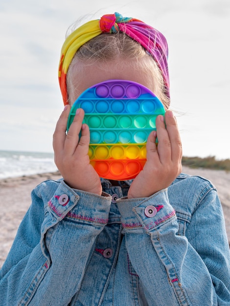 Photo happy child rainbow pop it toy having fun autumn sea trendy antistress sensory simple dimple fidget