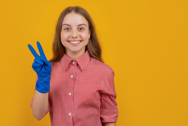 Happy child in rubber gloves on yellow background peace