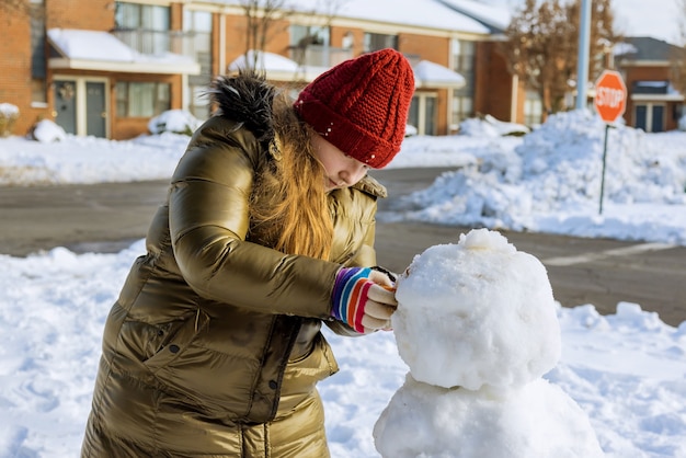 Happy child sculpts a snowman winter in park the snow on the playground