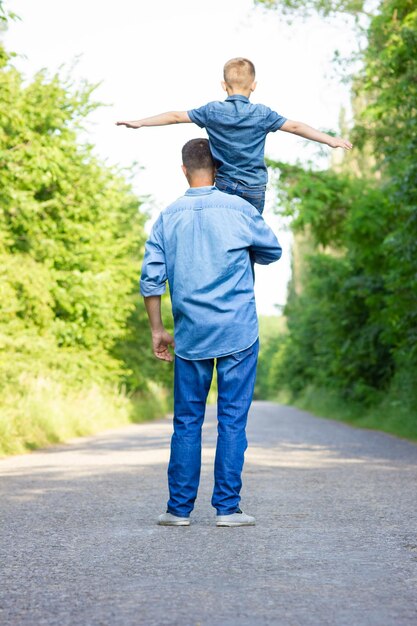 Happy child on the shoulders of a parent in nature on the way to travel