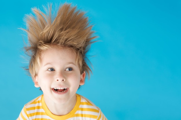 Foto bambino felice che grida su sfondo di carta blu bambino divertente appeso a testa in giù vacanze estive e concetto di viaggio