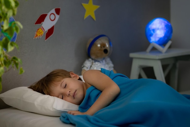 Happy child sleeping with toy rocket and teddy bear Kid pretend to be astronaut Imagination and children dream concept