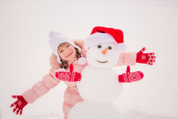 Happy child and snowman in winter park