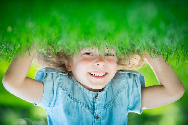 写真 緑の芝生の上に逆さまに立っている幸せな子春の公園で楽しんで笑っている子供健康的なライフスタイルのコンセプト