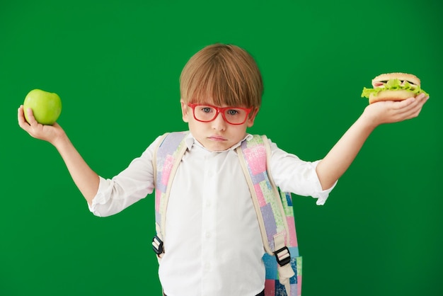 Happy child student against green chalkboard