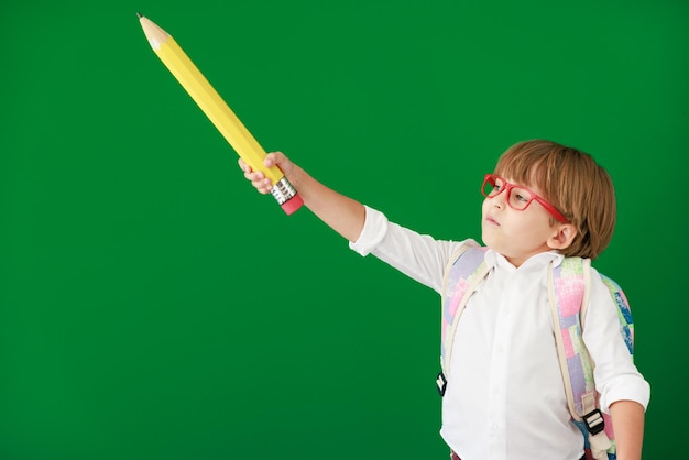 Studente bambino felice contro la lavagna verde