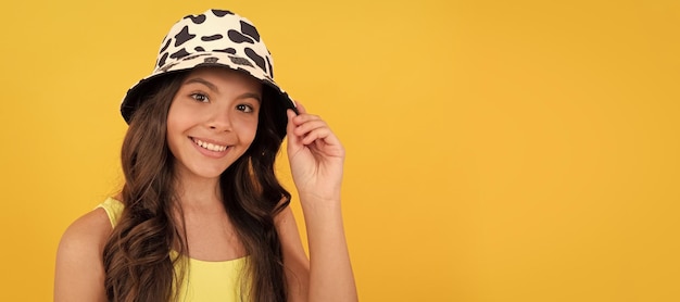 Happy child in summer bucket hat has curly hair on yellow background beach fashion child face