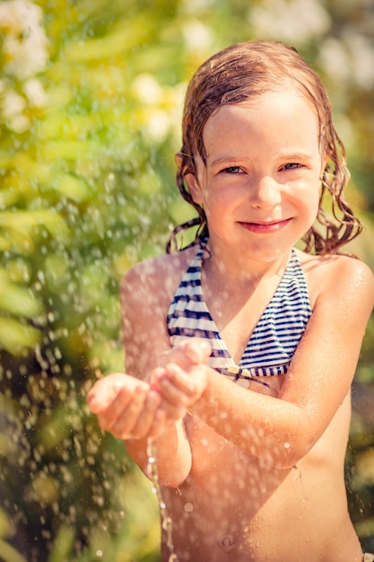 Счастливый ребенок принимает душ на открытом воздухе