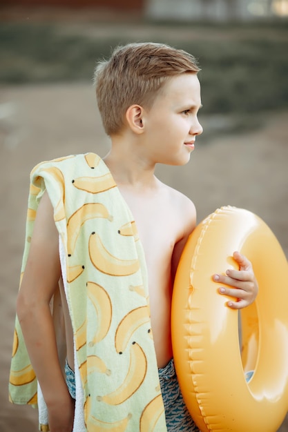 Happy child teen boy with yellow swimming ring lifebuoy near by river lake or pond vacation concept